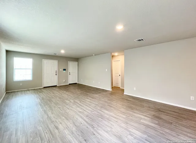 an empty room with wooden floor and window