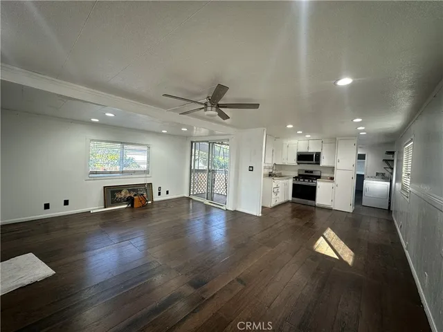 a view of an empty room with kitchen and window
