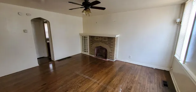 an empty room with wooden floor a ceiling fan and windows