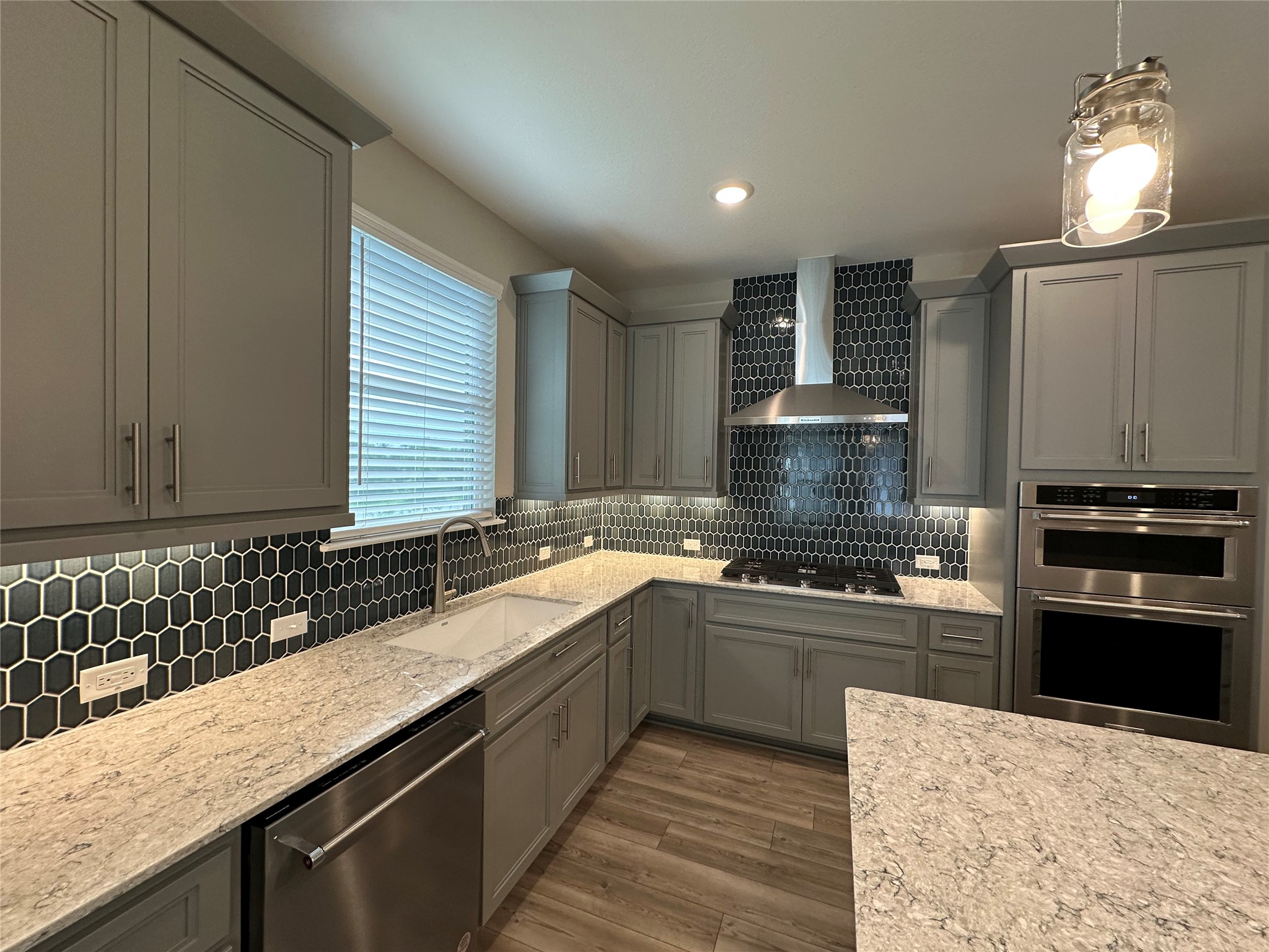 219 Coachsmith Street Georgetown, TX 78633 - Photo 10 of 25 Kitchen with tasteful backsplash, gray cabinets, wall chimney range hood, stainless steel appliances, and a sink