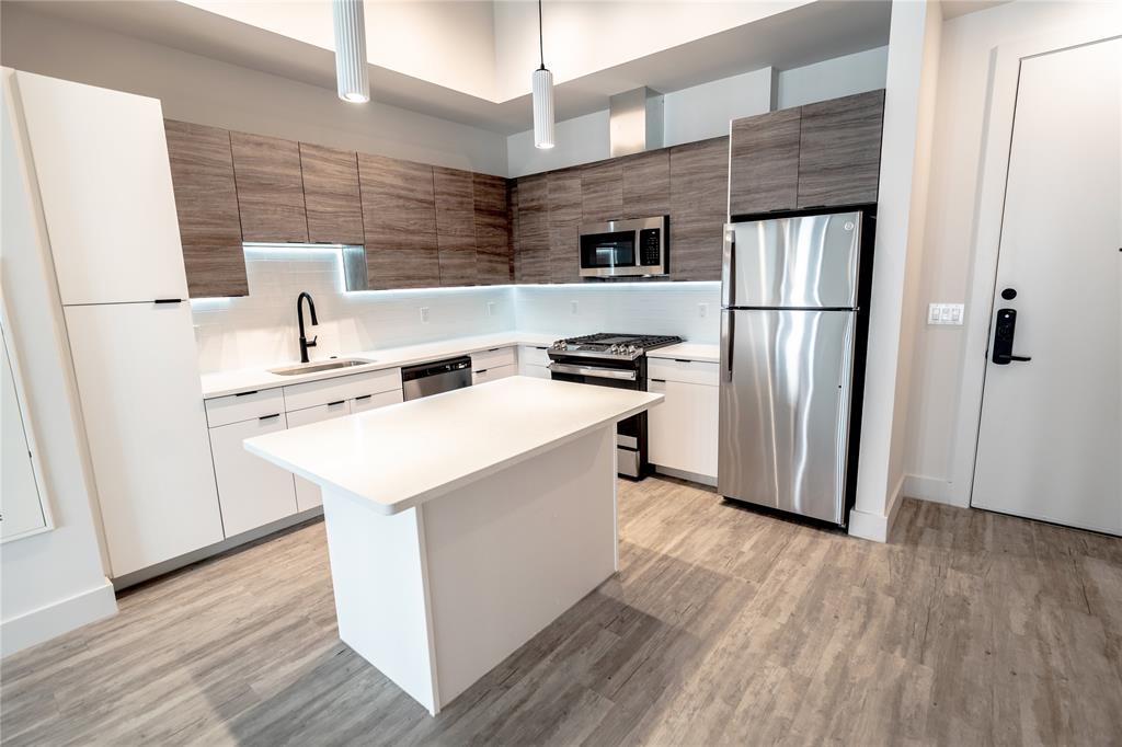 a kitchen with stainless steel appliances a refrigerator a sink and wooden floors