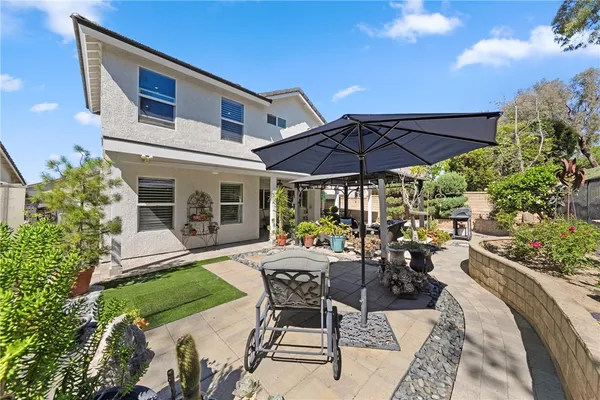 a view of a patio with couches table and chairs under an umbrella with a big yard