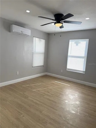 an empty room with wooden floor and windows