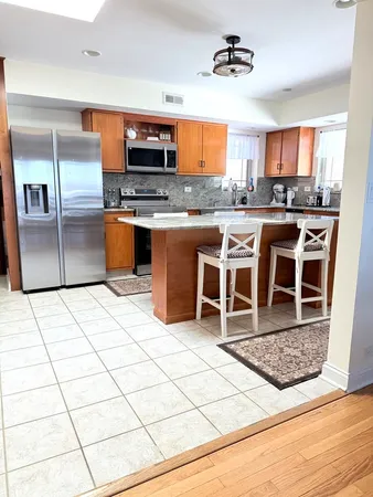 a kitchen with stainless steel appliances kitchen island granite countertop a stove a sink and a refrigerator