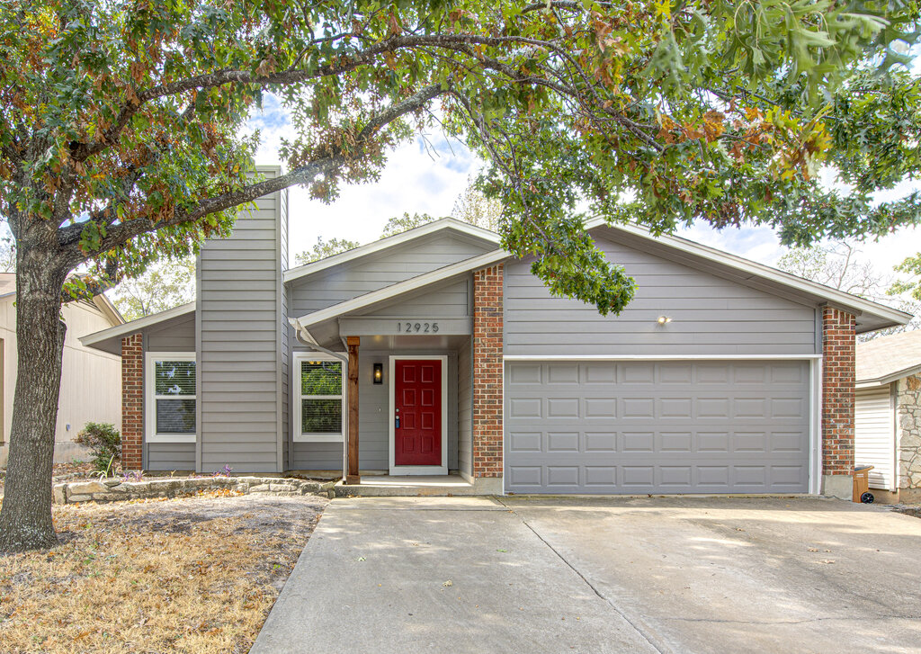 View of front facade featuring driveway, brick siding, and a garage