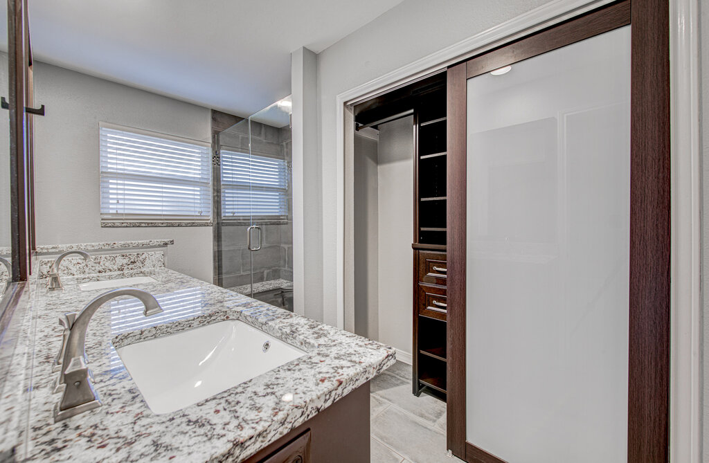 12925 Covington Trail Austin, TX 78727 - Photo 18 of 28 Full bathroom with double vanity, a shower stall, and a walk in closet