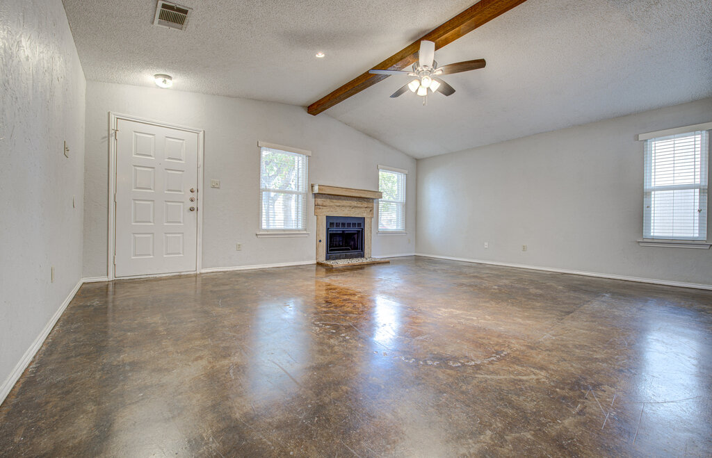 12925 Covington Trail Austin, TX 78727 - Photo 3 of 28 Unfurnished living room featuring a fireplace with raised hearth, a textured ceiling, a ceiling fan, and concrete floors