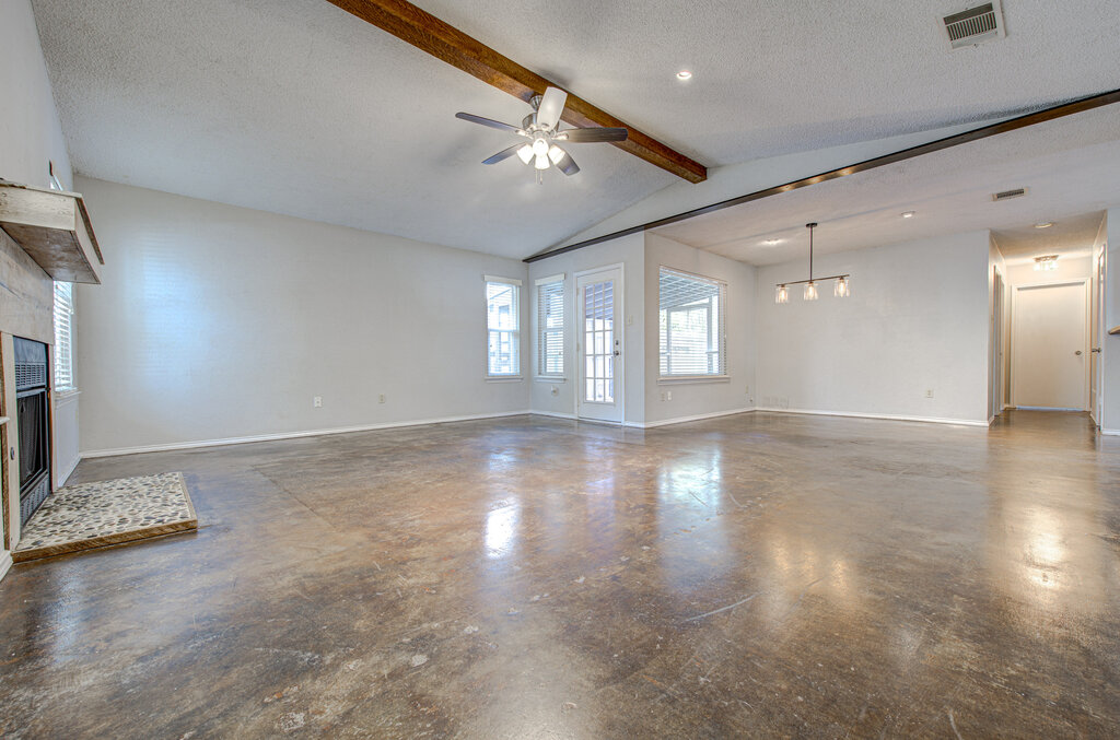 12925 Covington Trail Austin, TX 78727 - Photo 4 of 28 Unfurnished living room featuring a fireplace, a textured ceiling, concrete flooring, and ceiling fan