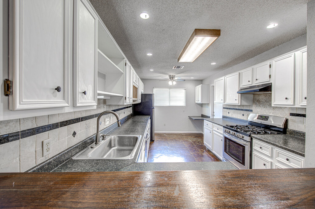 12925 Covington Trail Austin, TX 78727 - Photo 7 of 28 Kitchen featuring white cabinets, appliances with stainless steel finishes, a textured ceiling, dark countertops, and backsplash