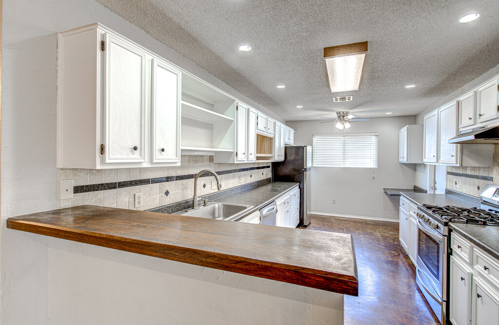 12925 Covington Trail Austin, TX 78727 - Photo 8 of 28 Kitchen with butcher block counters, backsplash, stainless steel appliances, white cabinetry, and a textured ceiling