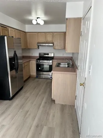a kitchen with stainless steel appliances a refrigerator a stove a sink and white cabinets