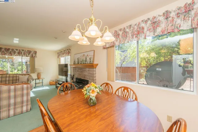 a view of a dining room with furniture a chandelier and large windows