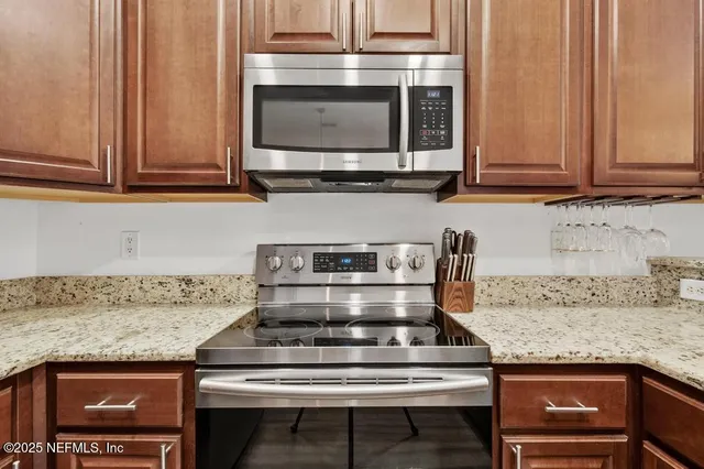 a kitchen with granite countertop wooden cabinets stainless steel appliances and a wooden floor
