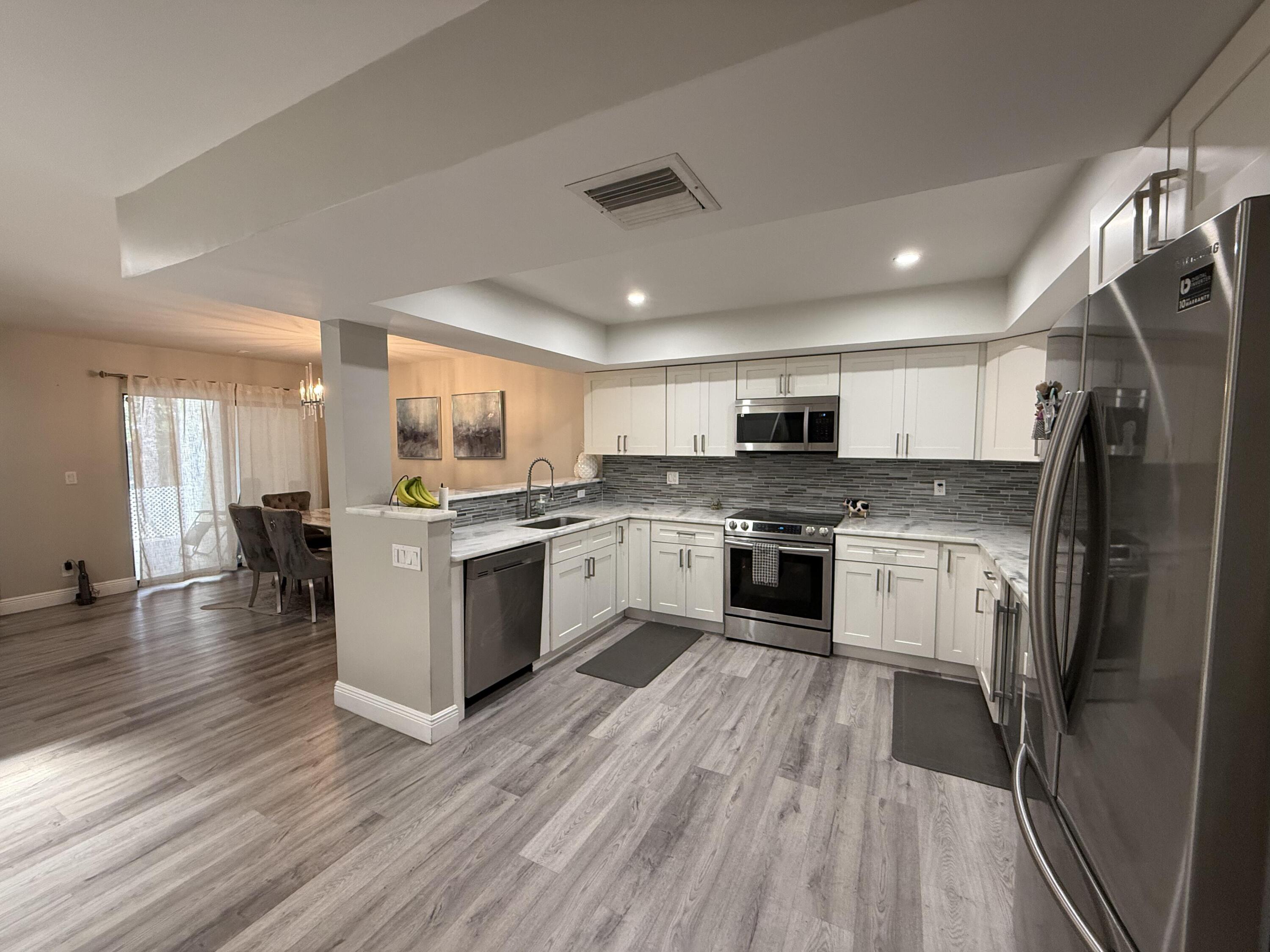 22874 Ironwedge Drive Boca Raton, FL 33433 - Photo 3 of 52 a kitchen with a center island wooden floor stainless steel appliances and windows