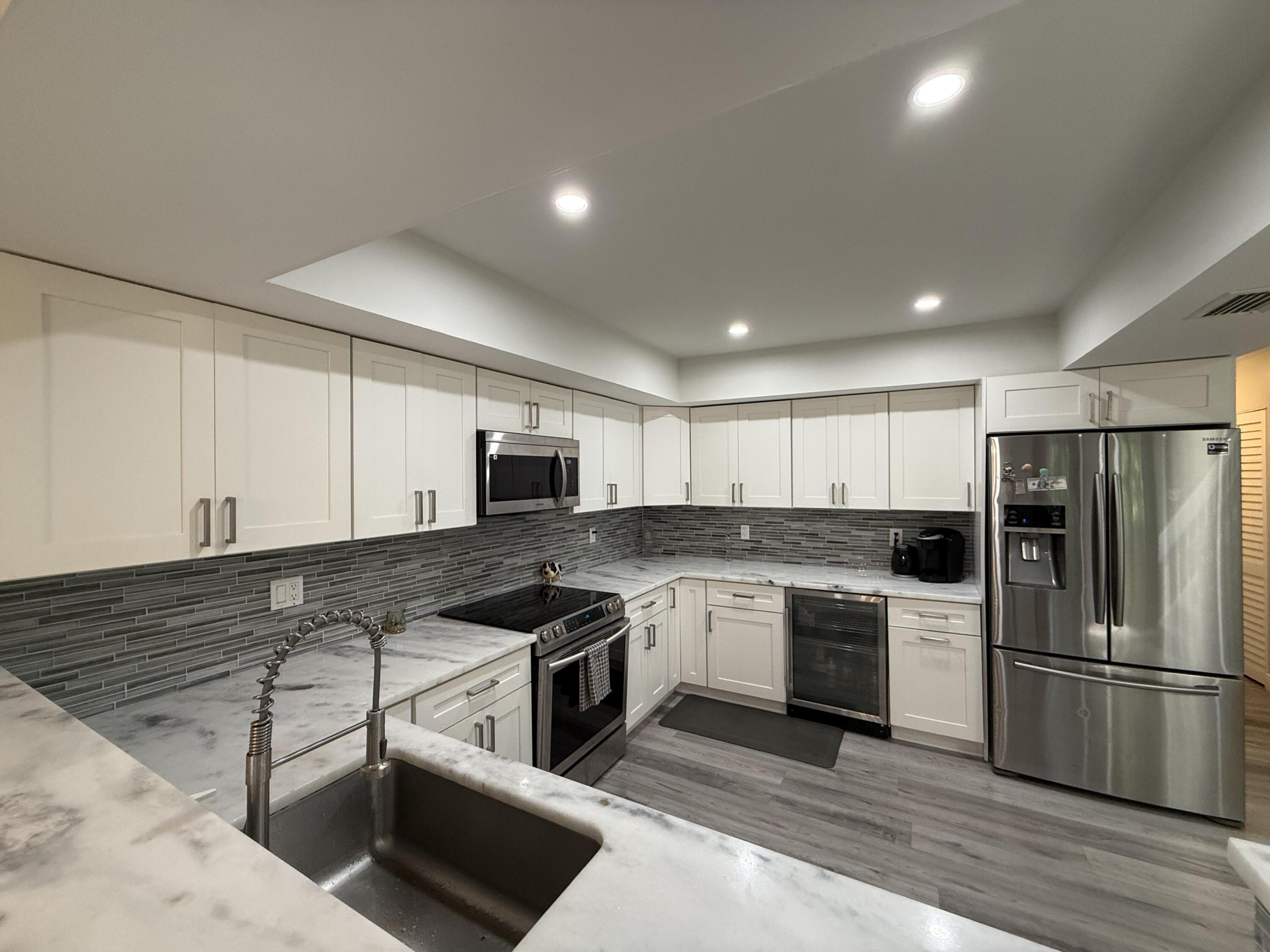 22874 Ironwedge Drive Boca Raton, FL 33433 - Photo 6 of 52 a kitchen with stainless steel appliances granite countertop a stove a sink dishwasher a refrigerator and white cabinets with wooden floor
