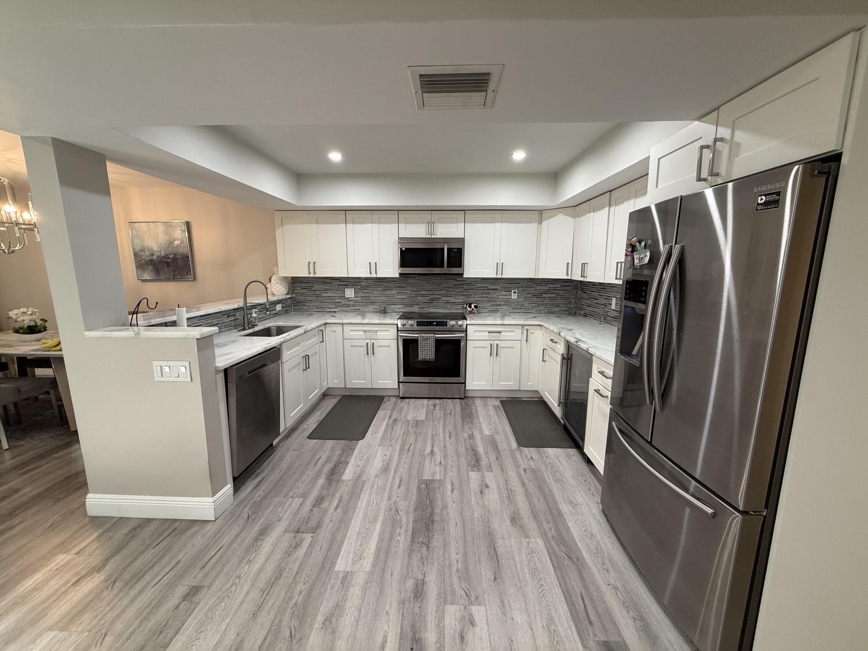 22874 Ironwedge Drive Boca Raton, FL 33433 - Photo 7 of 52 a kitchen with stainless steel appliances granite countertop a refrigerator a sink dishwasher a stove and white countertops with wooden floor