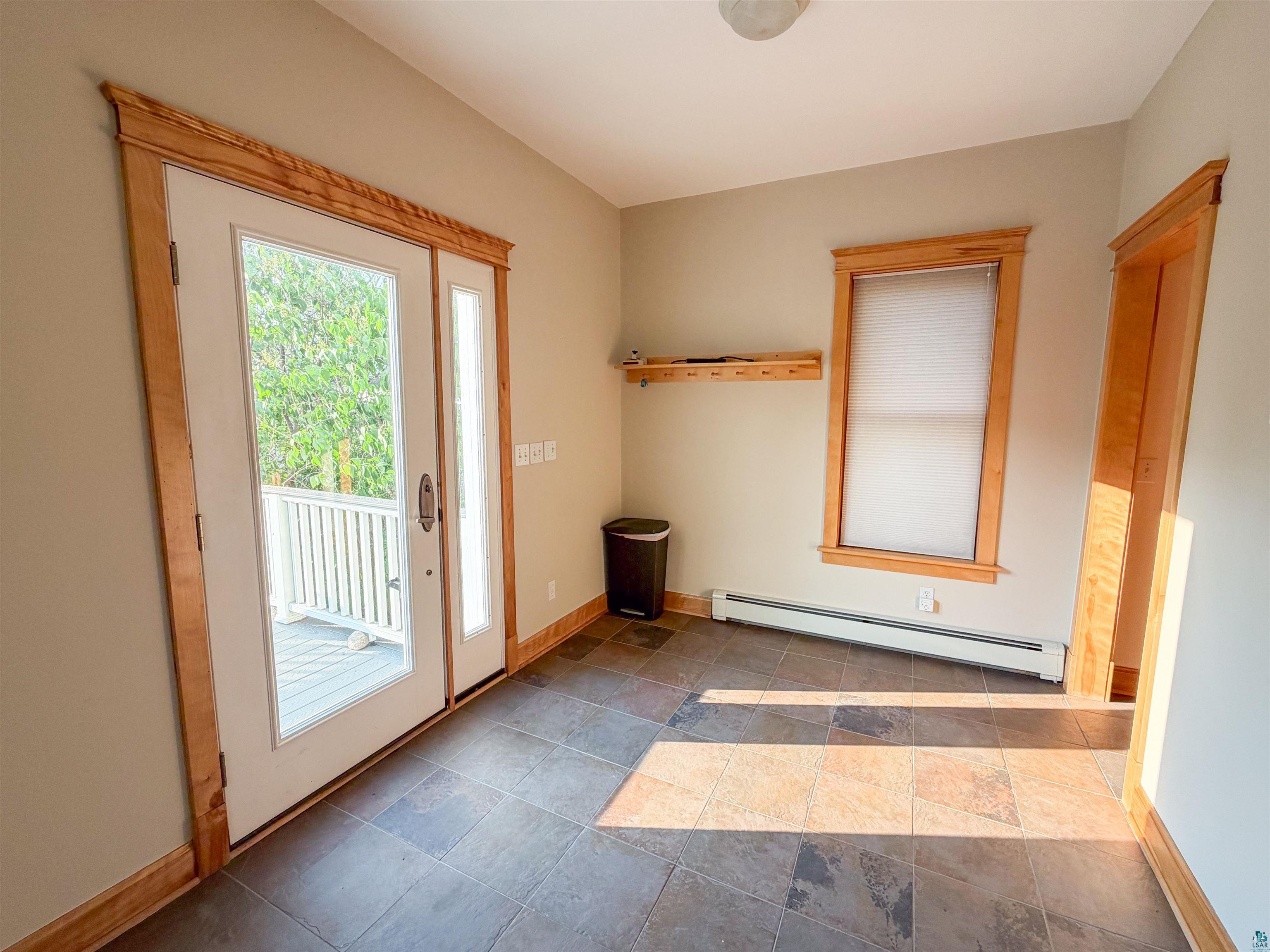 13 West 8th Street Duluth, MN 55806 - Photo 15 of 57 Entryway featuring a glass-paneled door leading to a deck, wood trim, tile flooring, and a window with blinds