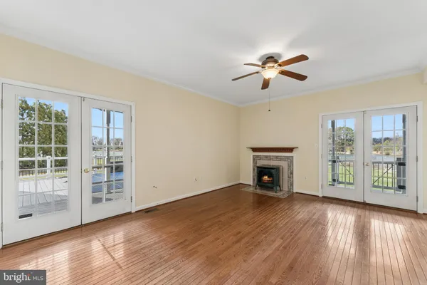 a view of a livingroom with wooden floor a ceiling fan and windows