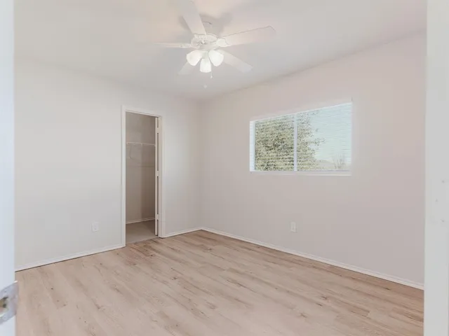 an empty room with a window and a ceiling fan