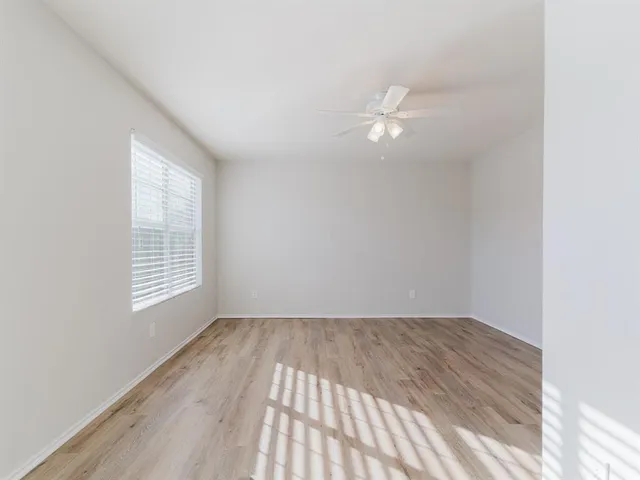 a view of empty room with wooden floor and fan