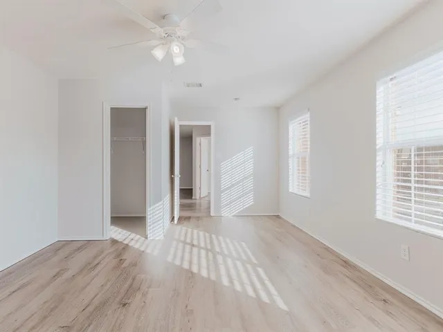 an empty room with wooden floor closet and windows