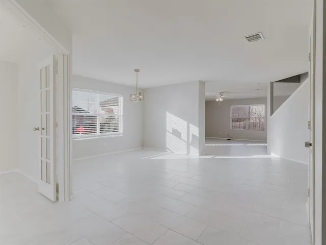 a view of an empty room with kitchen and window