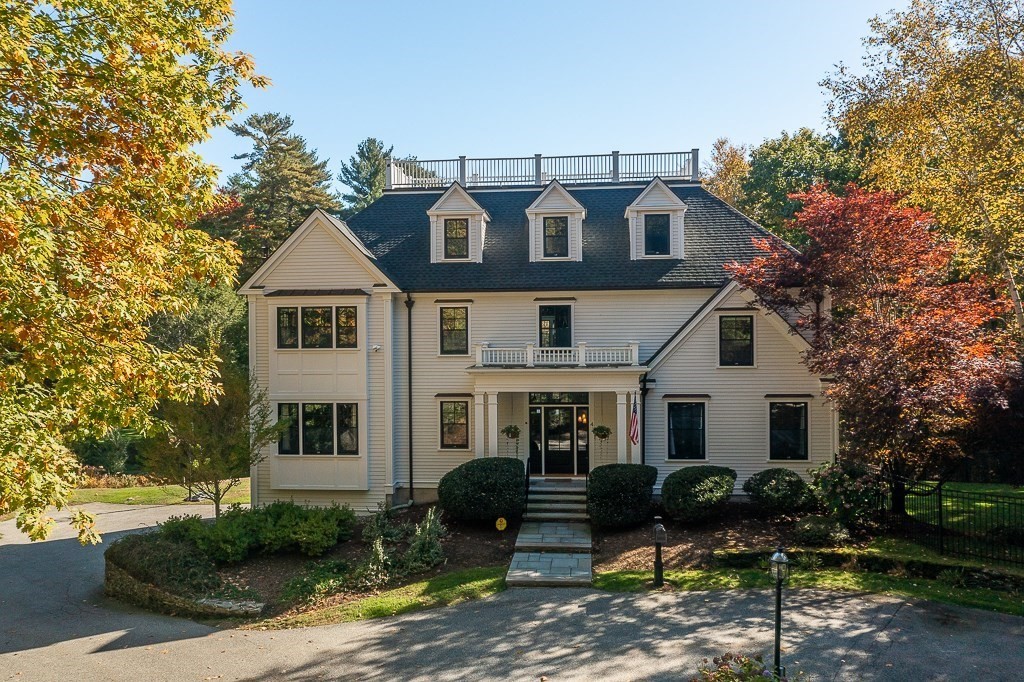 4 Bridle Path Lane Beverly, MA 01915 - Photo 1 of 42 a view of a white house with large windows and a table and chairs under an umbrella