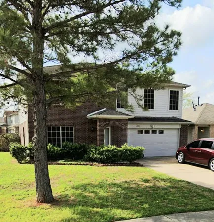 a view of a house with a big yard plants and large tree