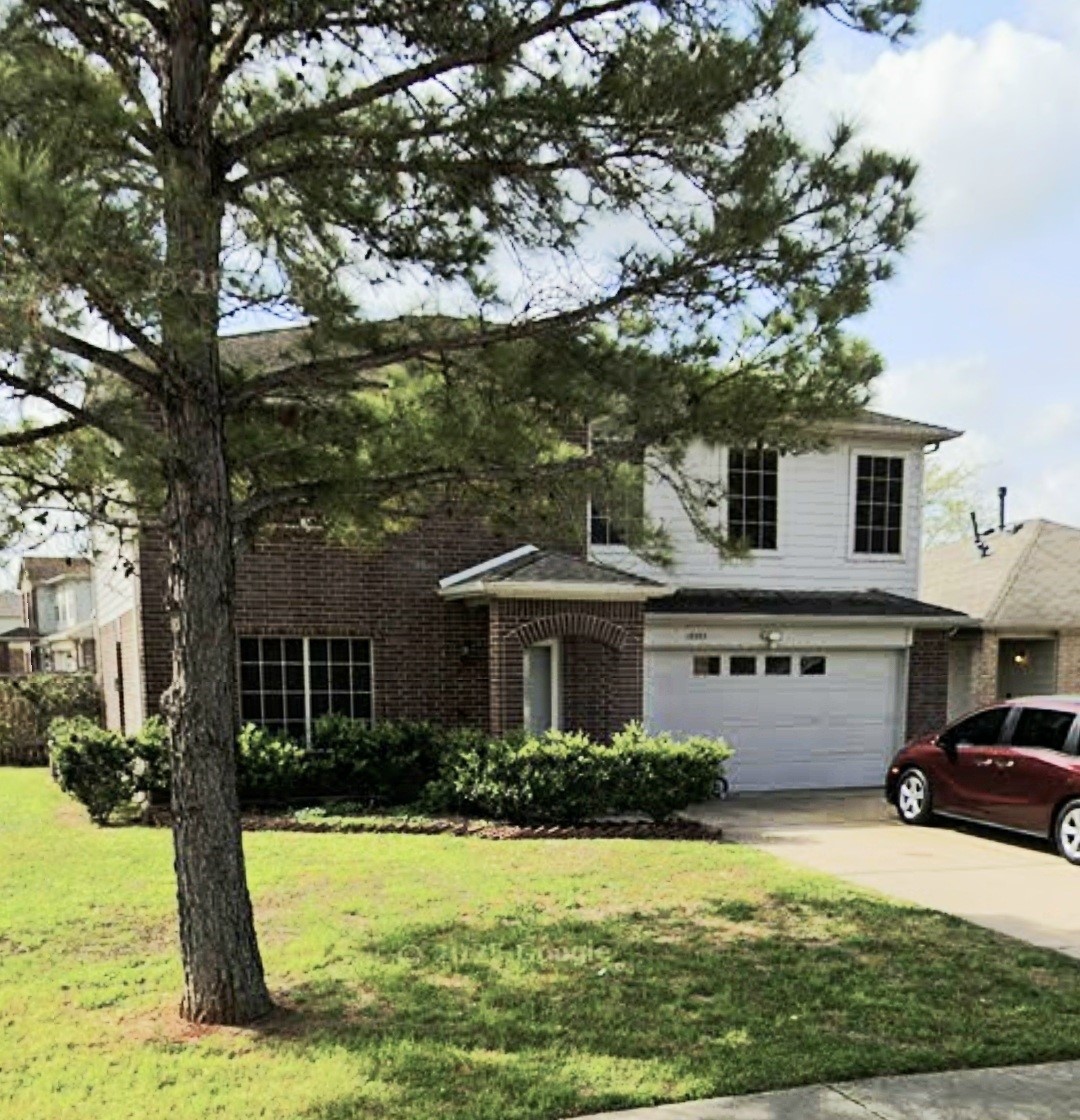 a view of a house with a big yard plants and large tree
