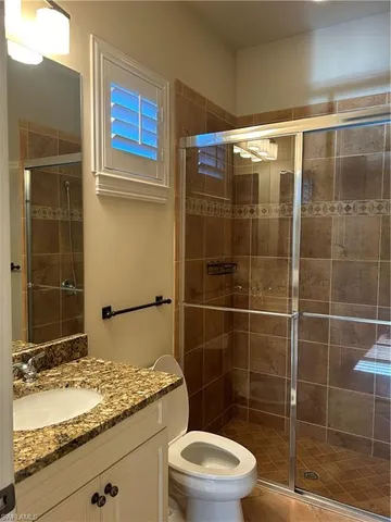 a bathroom with a granite countertop sink a toilet and shower