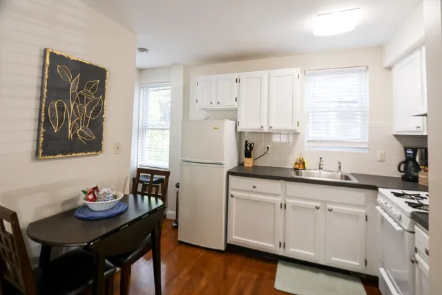 a kitchen with white cabinets and sink