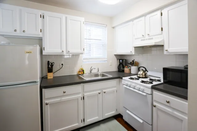 a kitchen with white cabinets and white appliances