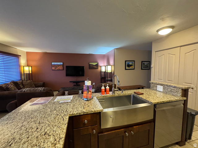 3439 Westwater Road Moab, UT 84532 - Photo 59 of 64 Kitchen with light stone counters, dishwasher, open floor plan, and dark brown cabinetry