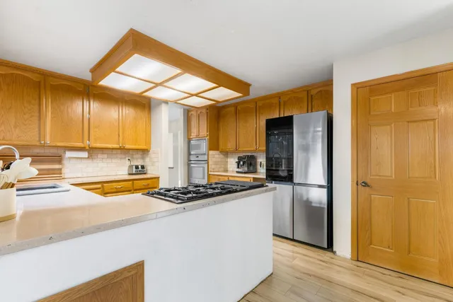 a dining hall with stainless steel appliances granite countertop a dining table chairs and a window