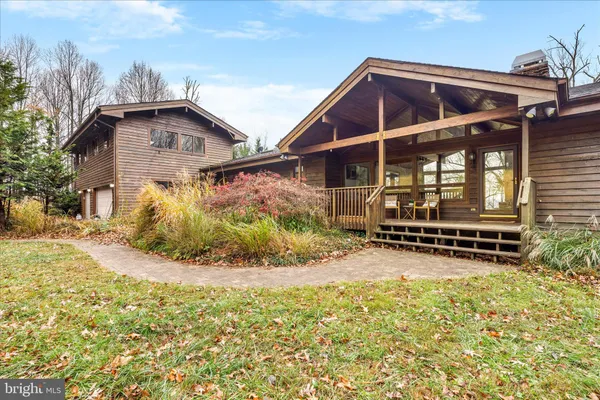 a view of backyard of house with wooden deck and outdoor seating