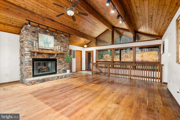 an empty room with wooden floor fireplace and windows