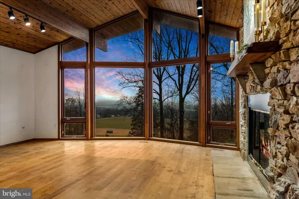 a view of an empty room with wooden floor and windows