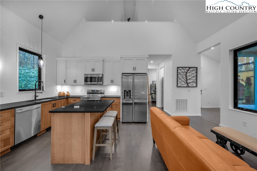 106 Jackpine Road Beech Mountain, NC 28604 - Photo 17 of 30 a kitchen with stainless steel appliances granite countertop a sink a stove a refrigerator cabinets and a dining table with wooden floor