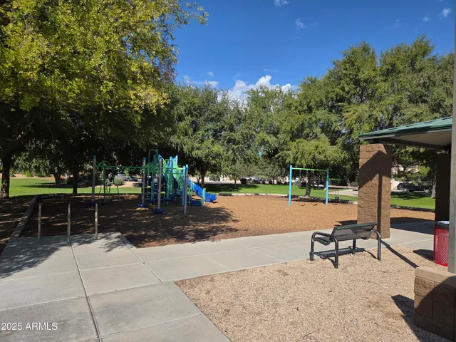 a view of a lake with table and chairs a fire pit and large trees