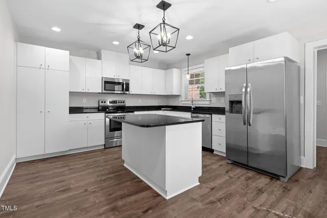 a kitchen with stainless steel appliances a refrigerator a stove a sink and chairs