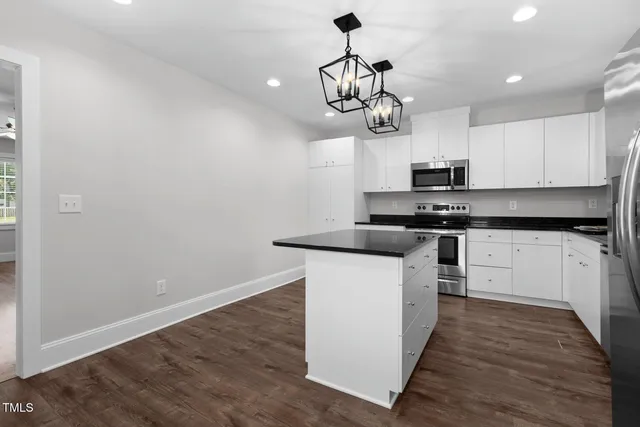 a kitchen with stainless steel appliances granite countertop a refrigerator a sink a stove a microwave and wooden floor