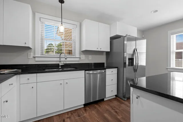 a kitchen with stainless steel appliances granite countertop a stove a sink and white cabinets