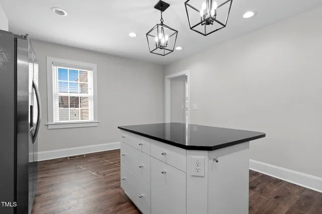 a kitchen with granite countertop white cabinets white appliances a sink and a window