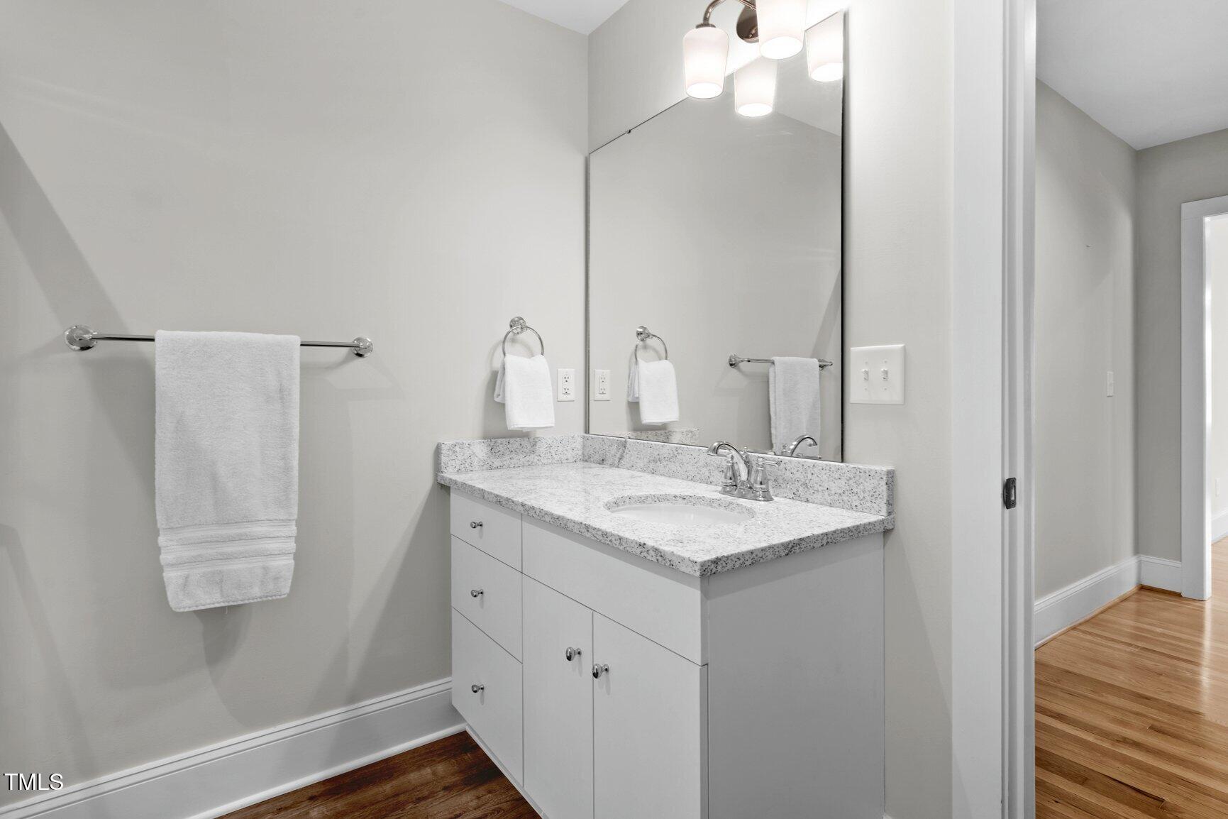 216 Whitfield Street Enfield, NC 27823 - Photo 24 of 31 a bathroom with a sink and mirror with wooden floor