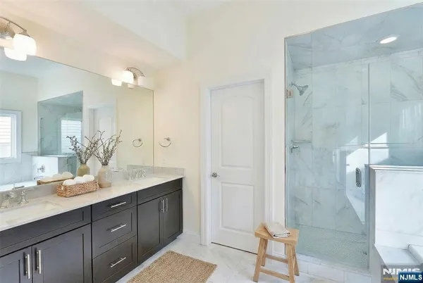 a bathroom with a granite countertop sink a mirror and a shower