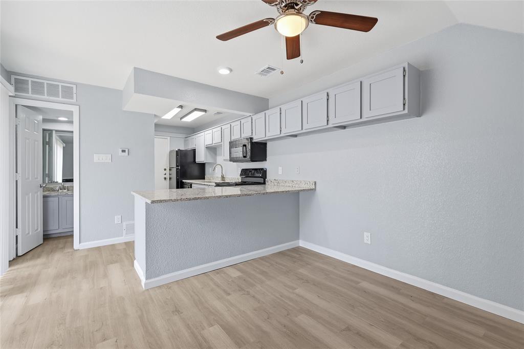 620 West Union Bower Road Irving, TX 75061 - Photo 4 of 22 Kitchen with a breakfast bar, ceiling fan, black appliances, light wood finished floors, and light stone countertops