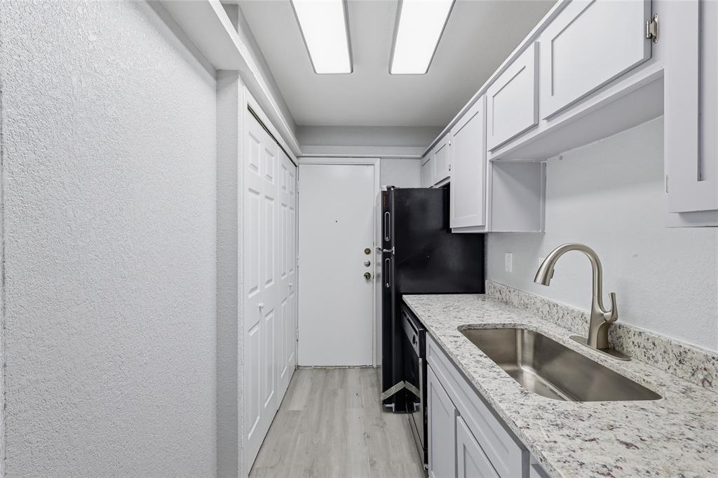 620 West Union Bower Road Irving, TX 75061 - Photo 6 of 22 Kitchen featuring a textured wall, light wood-style flooring, white cabinets, light stone counters, and dishwashing machine