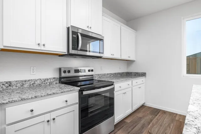 a kitchen with granite countertop white cabinets and stainless steel appliances