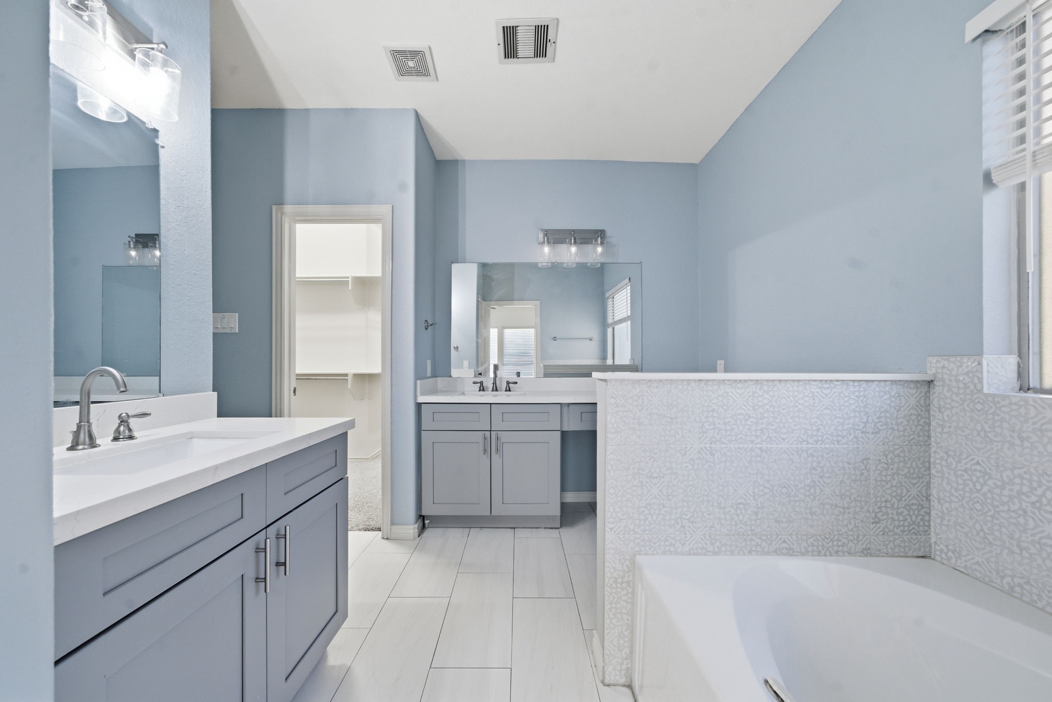 23139 Tranquil Spring Lane Katy, TX 77494 - Photo 13 of 22 Primary bathroom features a dual vanities with modern fixtures, and a spacious layout. It includes a large mirror, a separate bathtub, and ample natural light from a window, offering a fresh and inviting space.