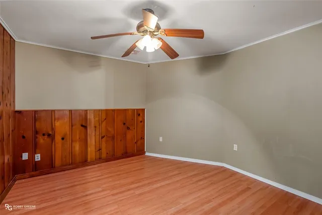 an empty room with wooden floor and fan